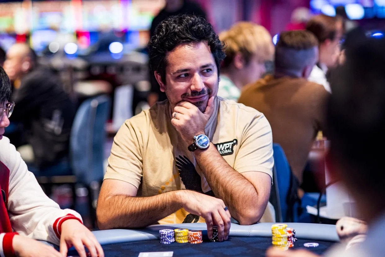 Ángel Guillén smiling at the poker table with a stack of chips in front of him, wearing a tan shirt and WPT Global patch