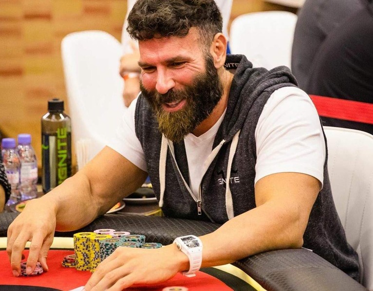 Dan Bilzerian smiling while playing poker, stacking chips during a live high-stakes poker game.