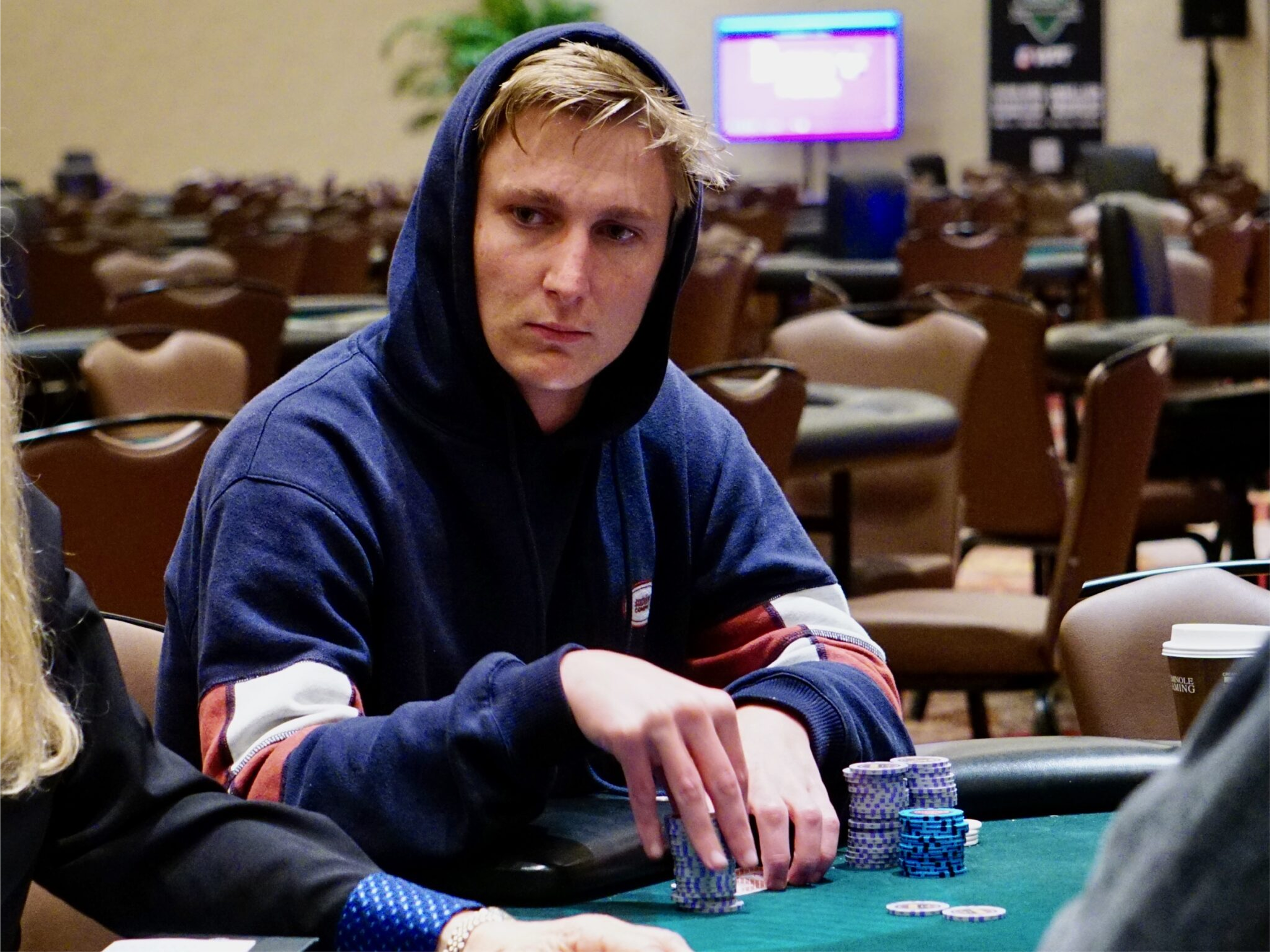 Connor Rash wearing a hoodie focused on gameplay at a live tournament table.