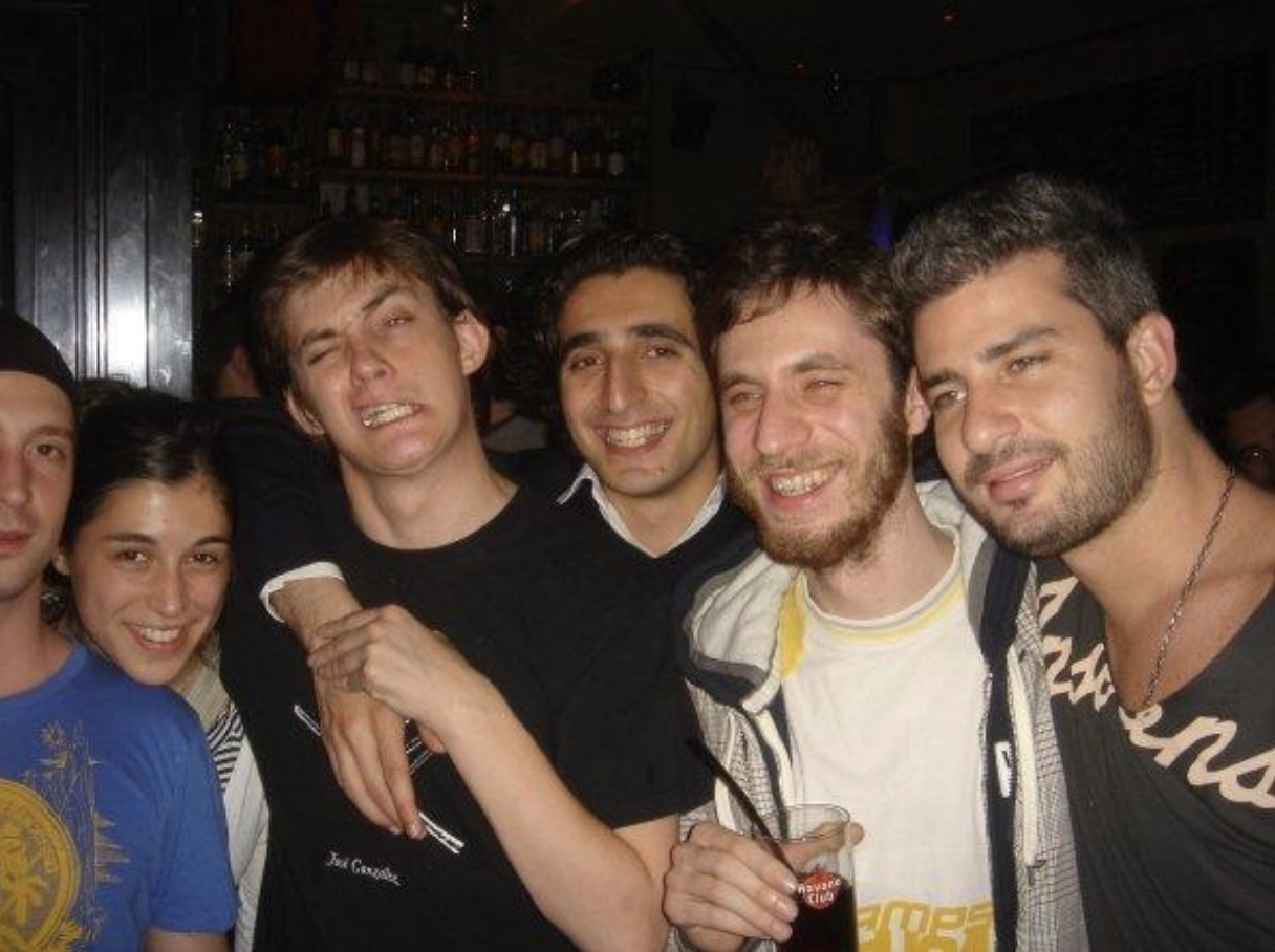 Group of friends smiling and posing together in a bar during a night out.