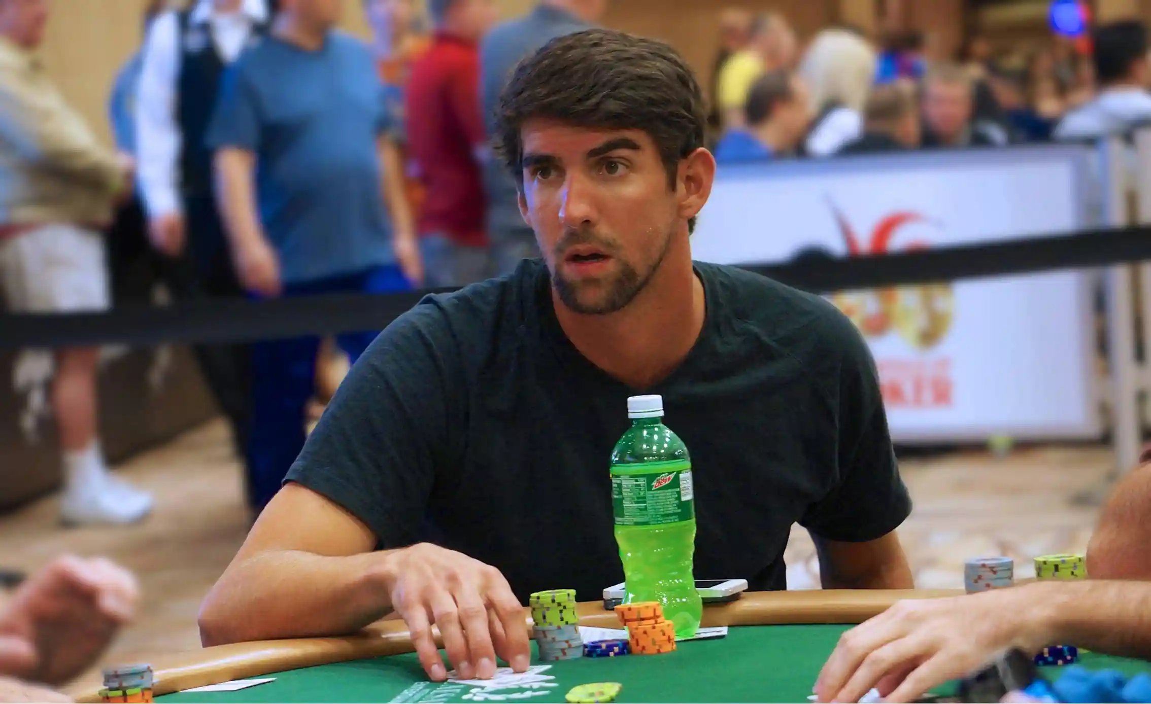 Focused Olympic swimmer seated at a live poker table arranging colorful chip stacks.
