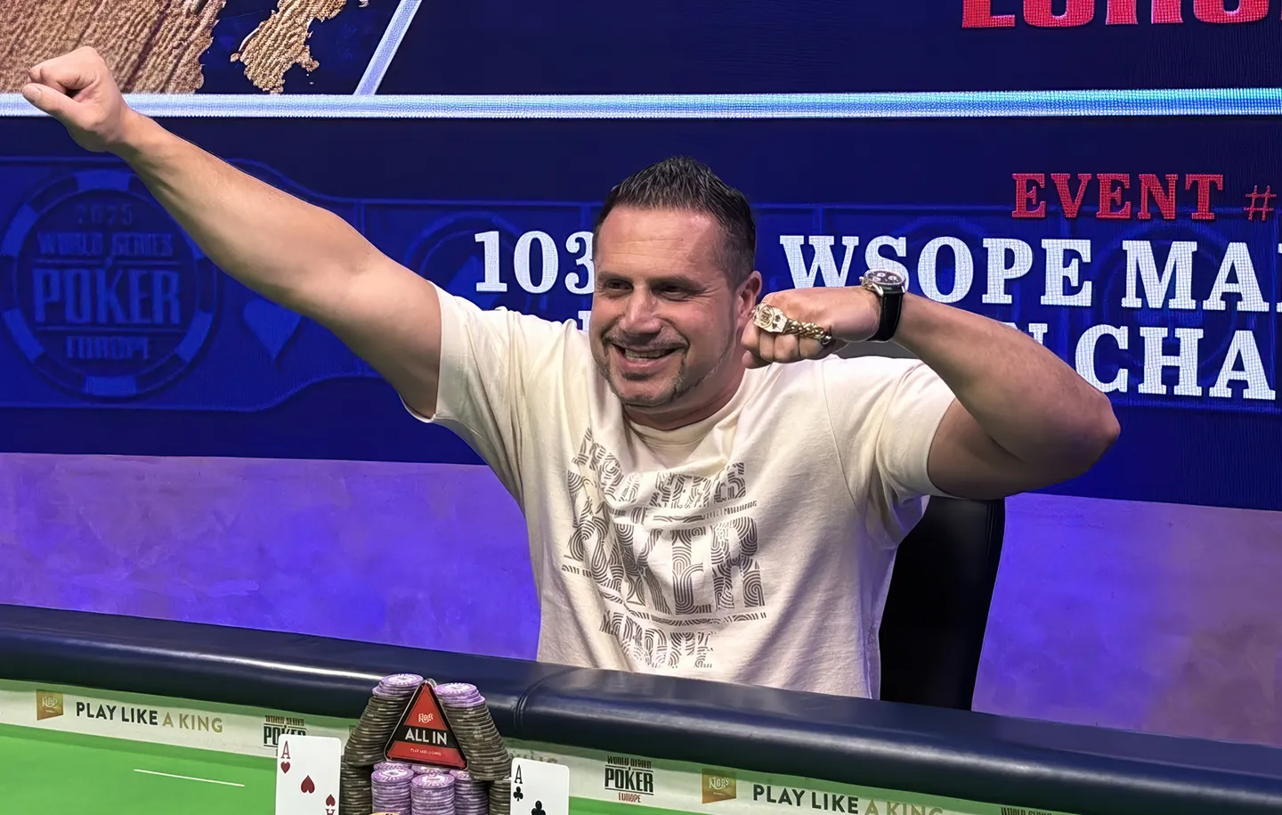Daniel Pidun celebrating victory at the WSOP Europe Main Event final table wearing a cream shirt with championship ring and chips stacked in front.