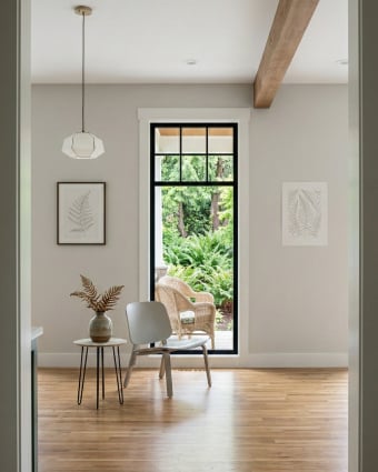 Professional painter applying white paint to a residential interior wall with a roller.