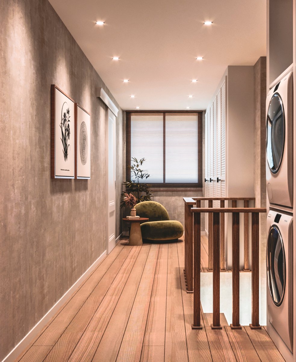 Bright upper-floor landing area in a duplex apartment in Amsterdam with custom white shutter wardrobes, wooden balustrade staircase and cozy green lounge chair by the window