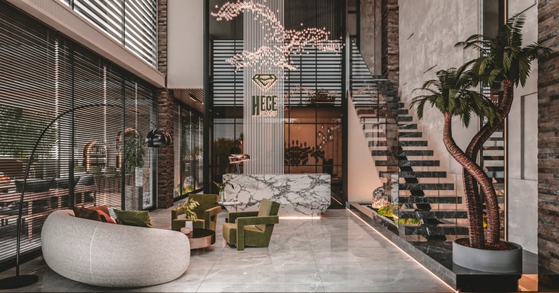 Double-height office reception lobby with marble desk and sculptural chandelier in Yenişehir Mersin