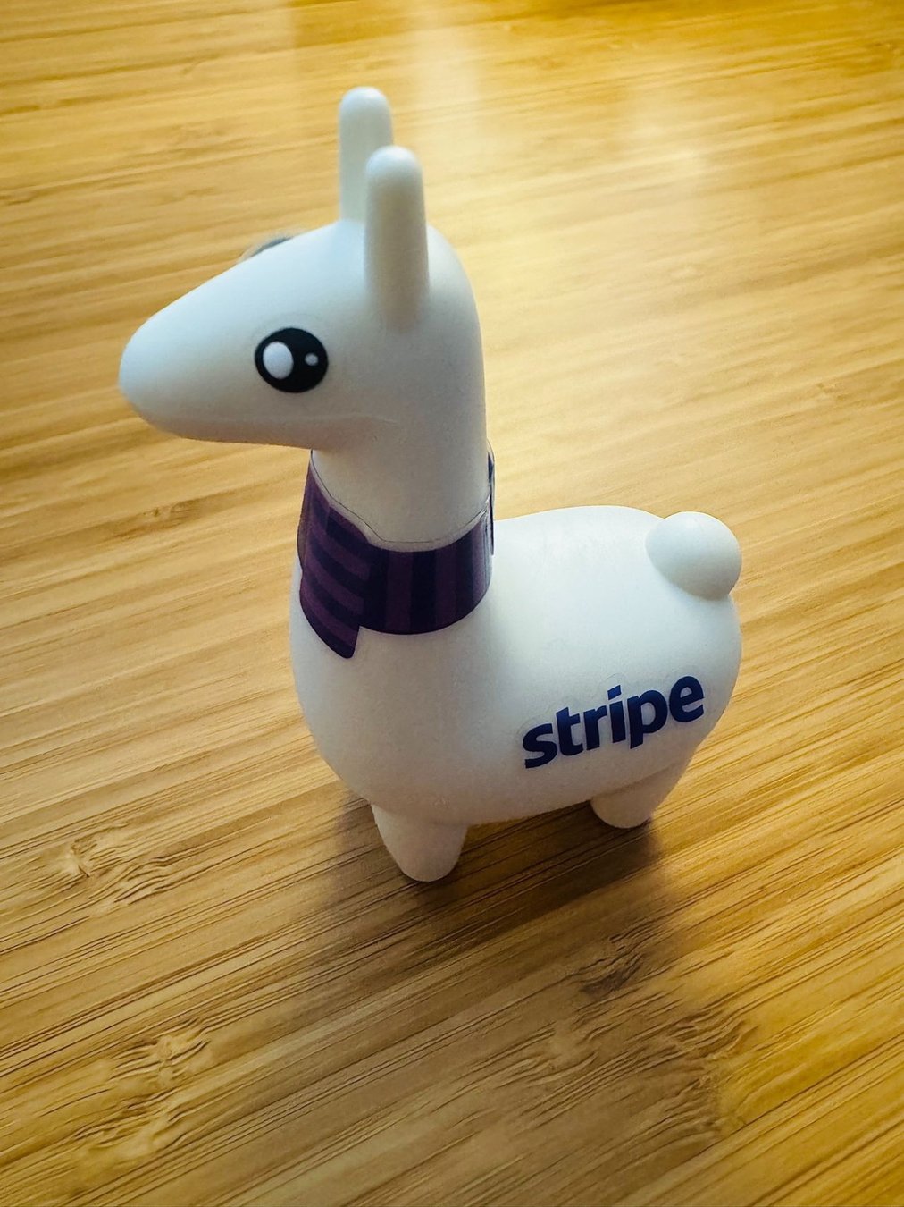 A little llama figurine with the stripe logo on it