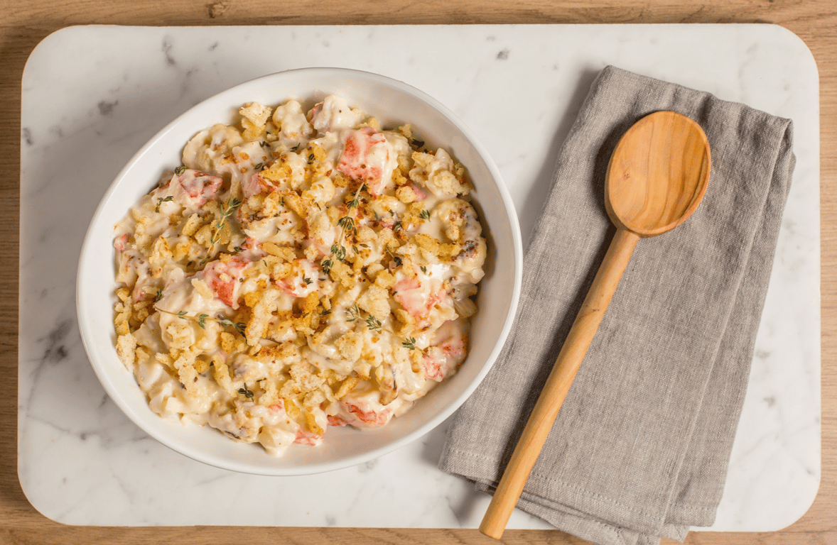 Food in a white bowl next to a wooden spoon