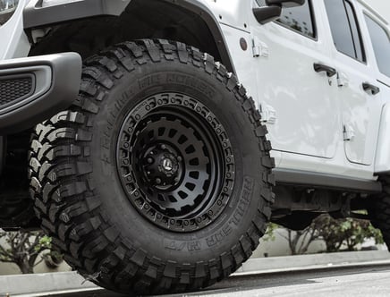 Close-up of a white vehicle with a large, rugged off-road tire and black alloy wheel.