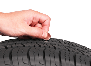 Someone uses a copper penny to check the tread of a tire.