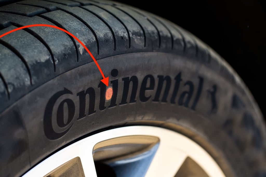 Close-up of a Continental tire with a red arrow pointing to a marked area on its sidewall.