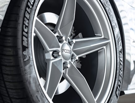 Close-up of a silver alloy wheel with a five-spoke design, a branded center cap, and a MICHELIN tire.