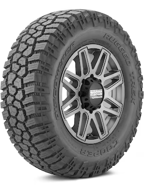 A rugged all-terrain Cooper Discoverer Rugged Trek tire with deep treads and a metallic wheel rim, designed for off-road use.