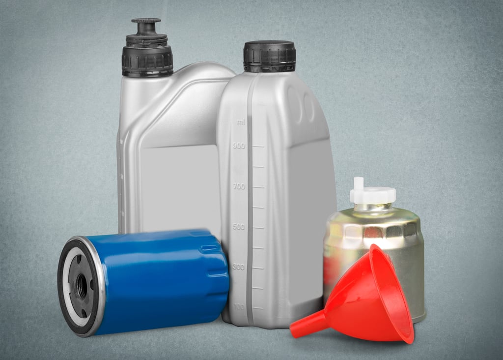Two grey plastic motor oil containers, a blue oil filter, a metallic canister, and a red funnel on a grey background.