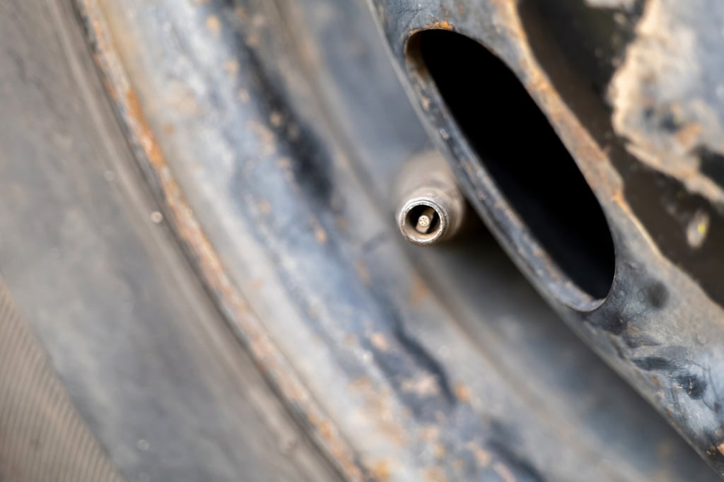 Close-up of a tire valve on a metal rim with visible rust.