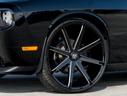 Close-up of a black car featuring a large, multi-spoke alloy wheel from the brand Dub, highlighting the front headlight and side marker light.