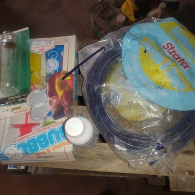 Coiled blue garden hose with cleaning supplies and hardware - Image 2 of 2