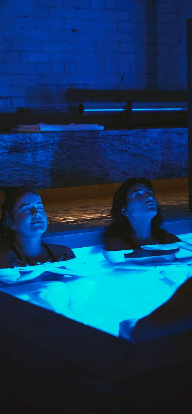 Ambiance nocturne au sein de RECESS — l'espace de bain de glace éclairé sous une lumière bleue profonde.