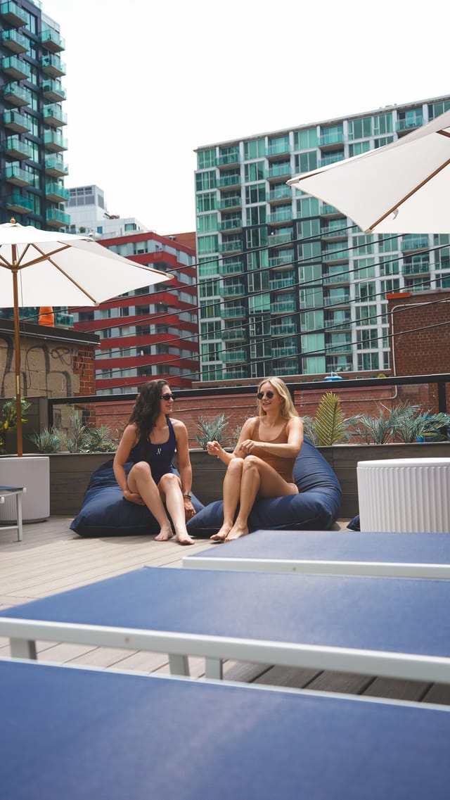 Membres sur la terrasse RECESS — sièges lounge sur le toit avec le centre-ville de Montréal en arrière-plan.