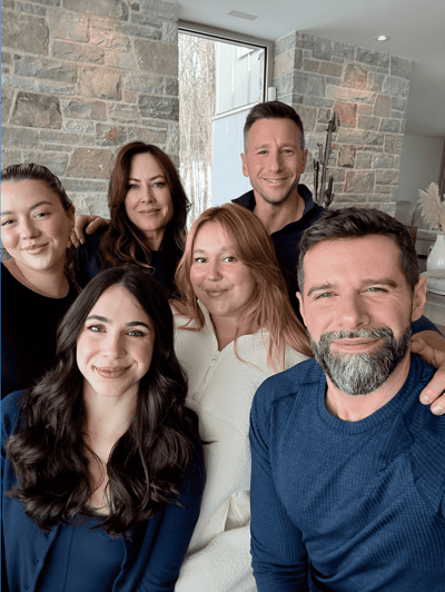 Une personne portant des lunettes et un haut sombre, assise avec assurance