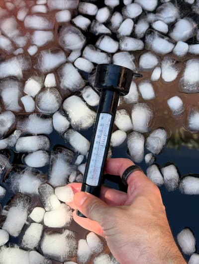 Main tenant un thermomètre dans de l'eau glacée