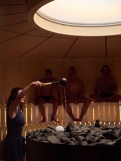 Guide versant de l'eau sur les pierres du sauna pendant un aufguss
