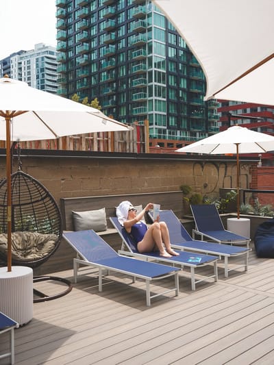 Invitée lisant sur une chaise longue en toit-terrasse face à la ville