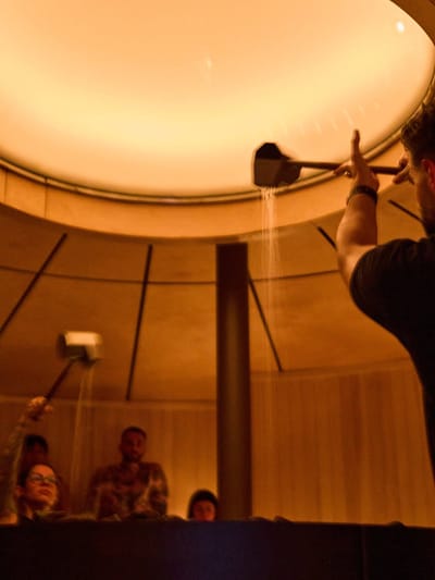 Lumière ambrée pendant qu'on verse de l'eau dans le sauna circulaire