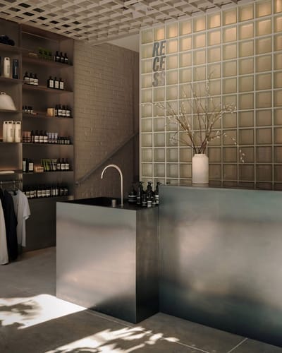 Hall RECESS avec étagères Aesop et comptoir d'accueil en métal brossé