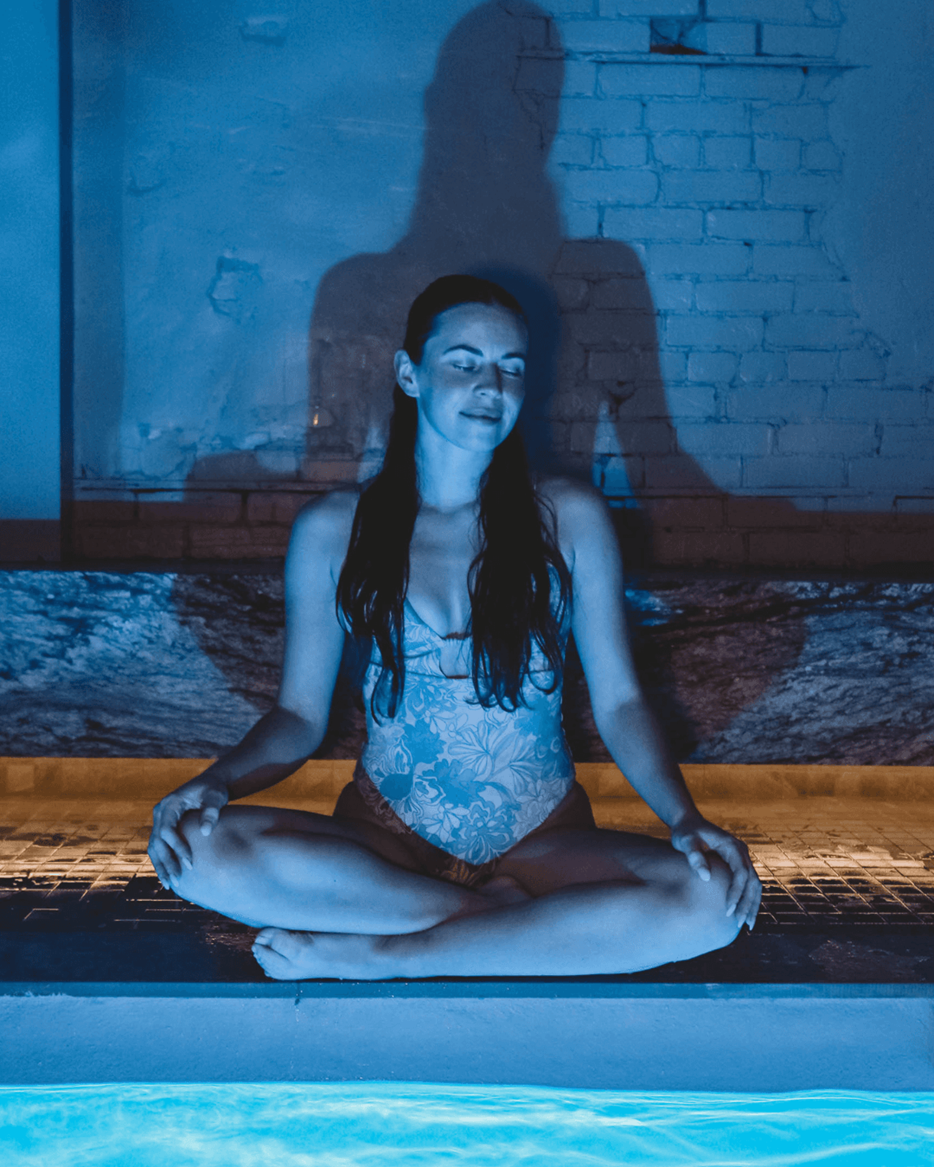 Lumière chaude et vapeur enveloppant le bassin thermal RECESS — ambiance de détente profonde.