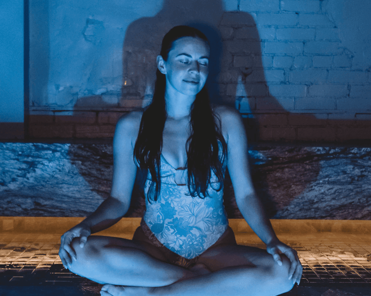 Lumière chaude et vapeur enveloppant le bassin thermal RECESS — ambiance de détente profonde.