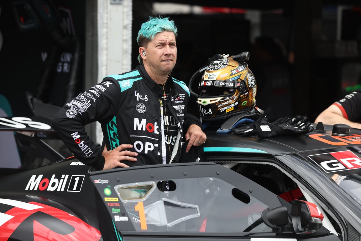 Chaz Mostert with teal hair stands beside his Mobil 1 Toyota Supercar in the garage.