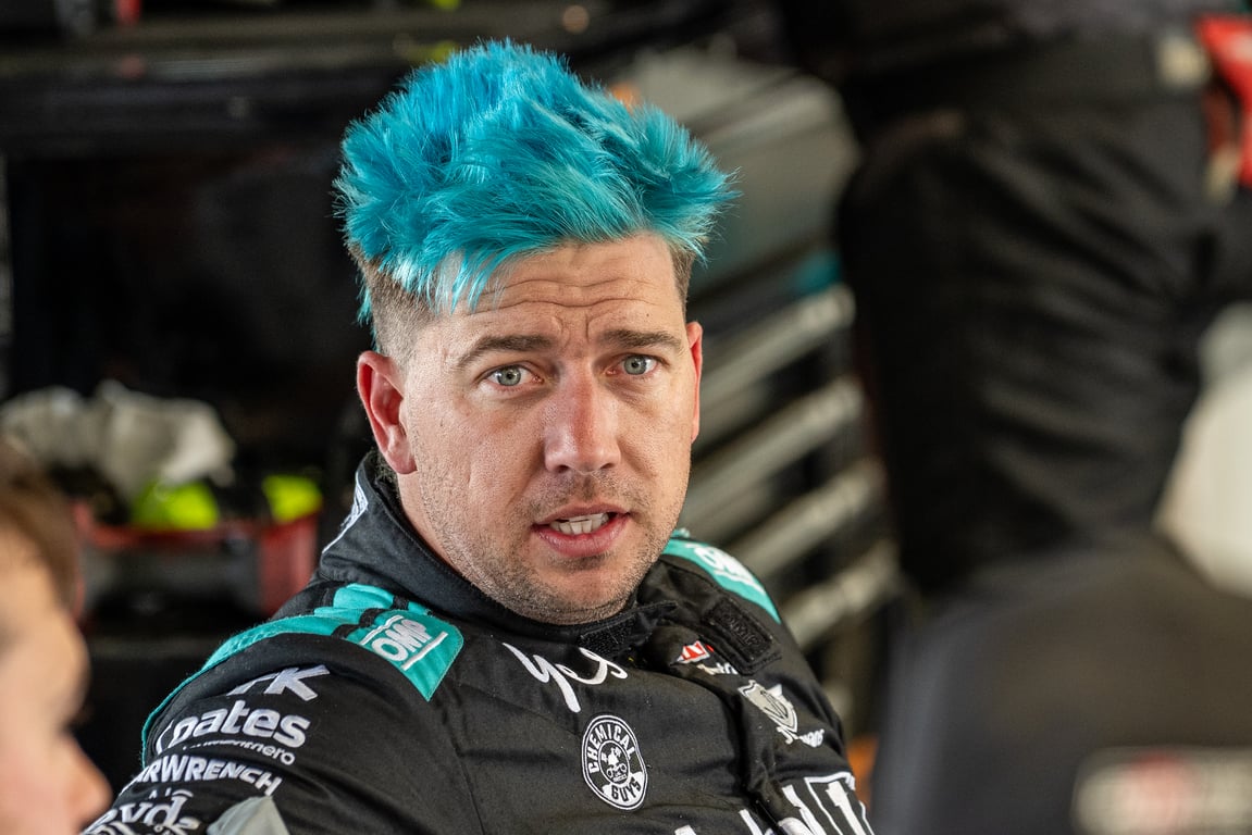 Chaz Mostert with teal-blue hair in his racing suit in the garage.
