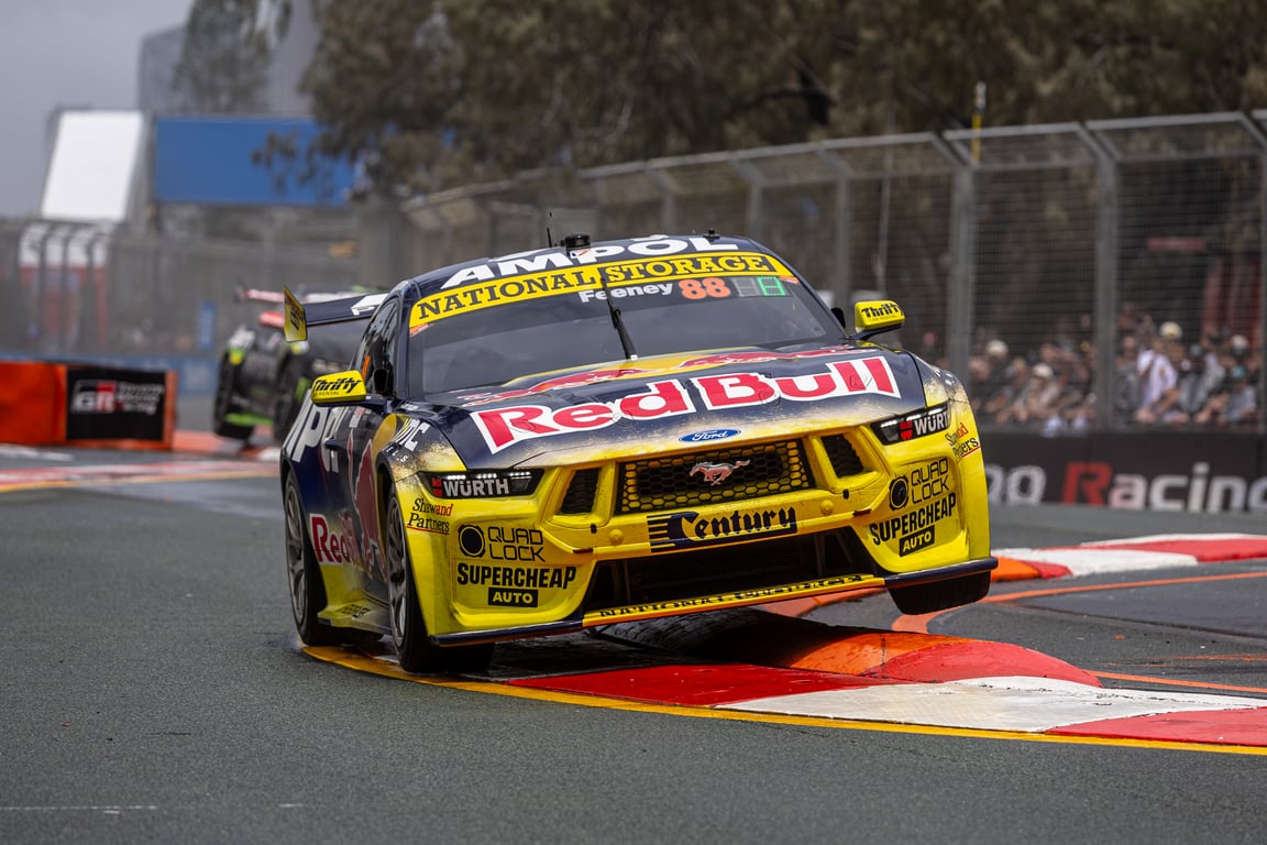 Red Bull-liveried Ford Mustang Supercar number 88 bounces over a kerb on a street circuit.