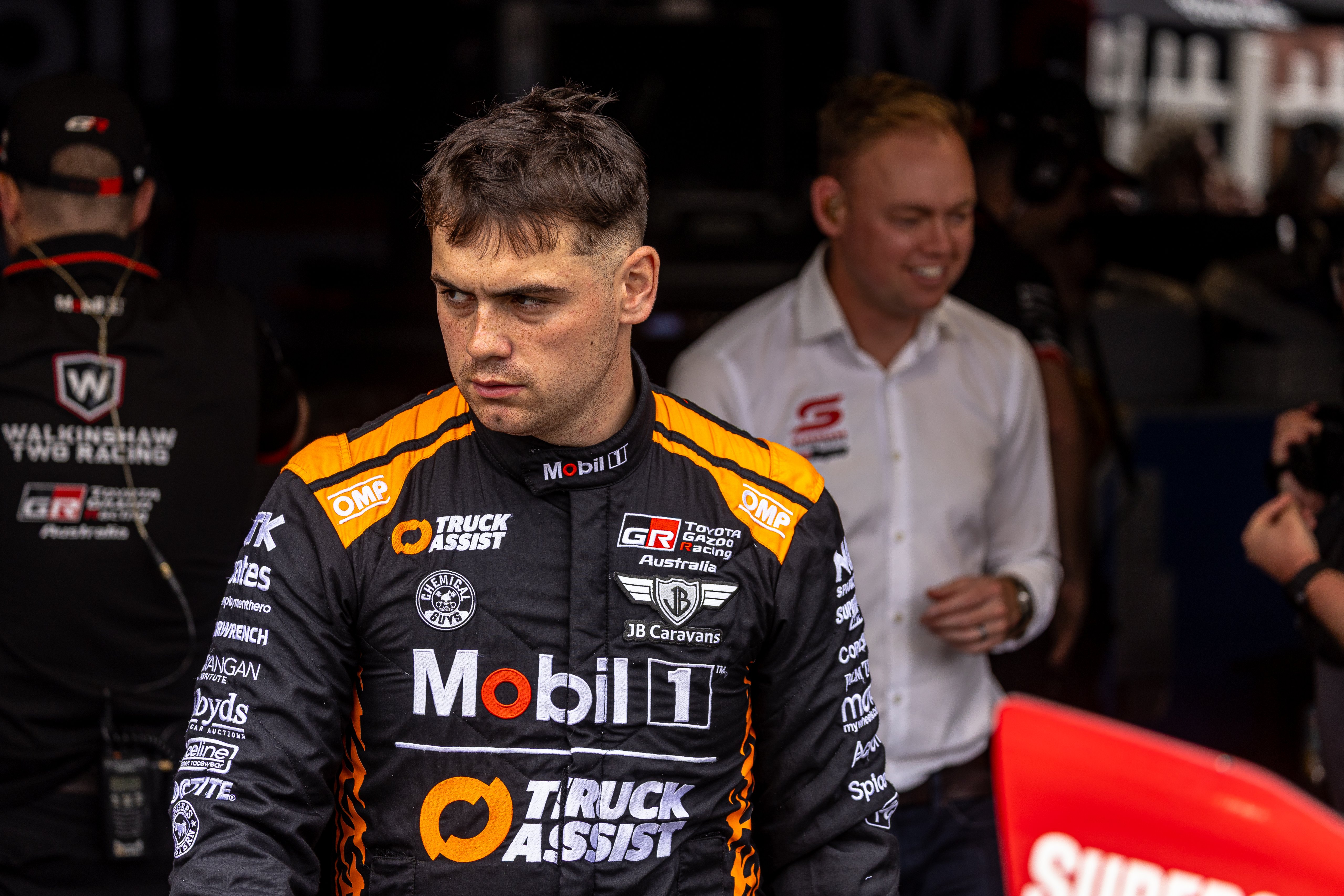 Ryan Wood in racing suit in pit lane with Chad Neylon smiling behind him.