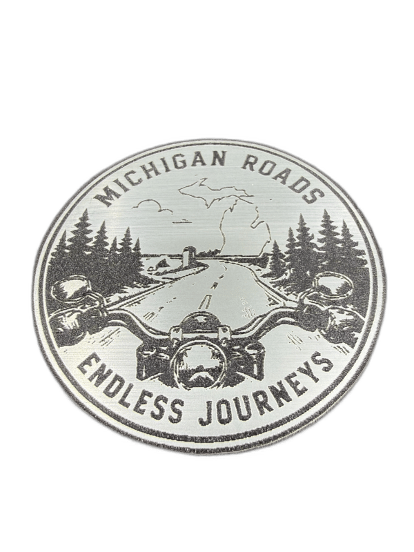 Michigan Roads Endless Journeys oval silver emblem with motorcycle and pine forest scene