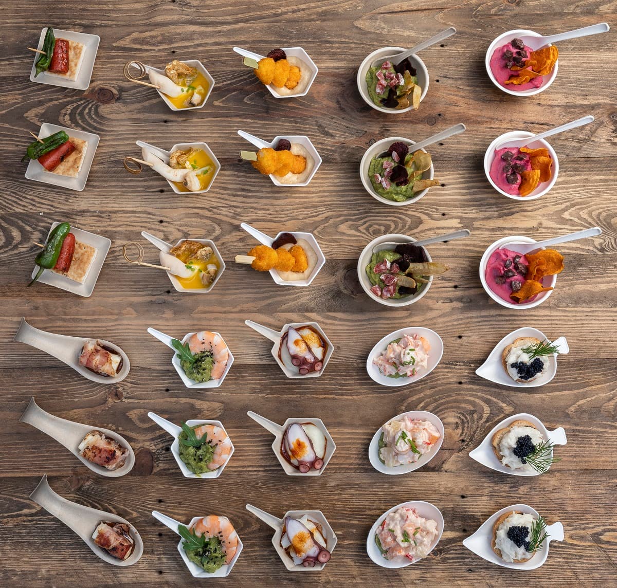 Vista dall’alto di diversi cucchiaini da degustazione con antipasti