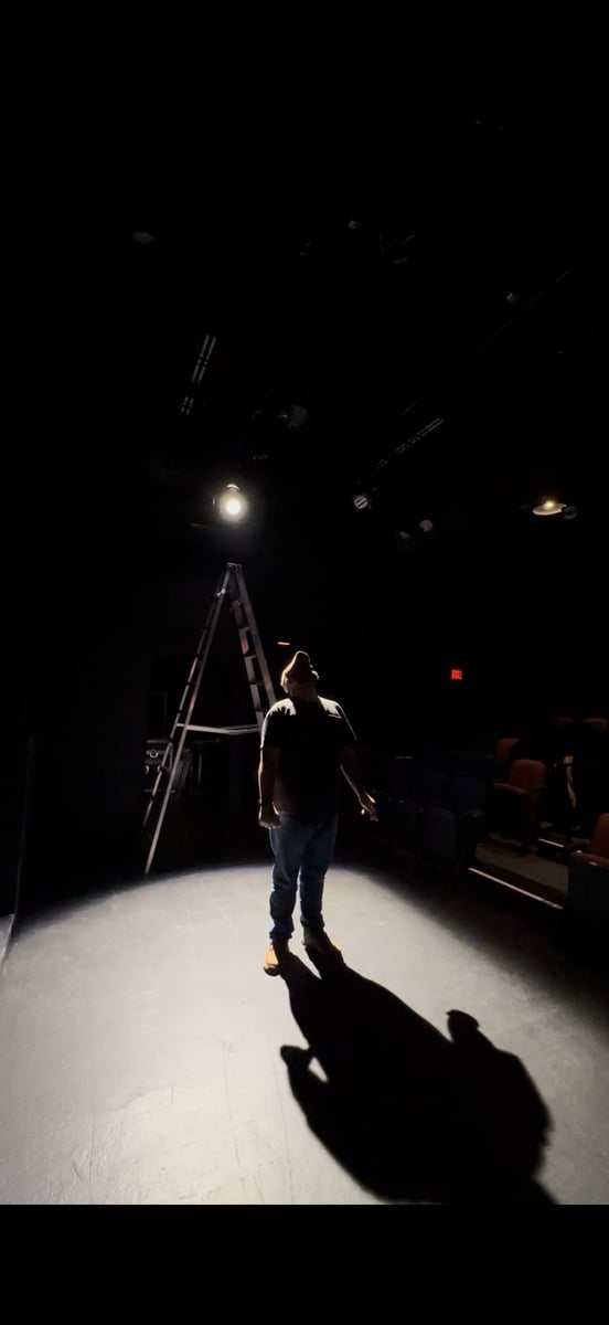 A lone figure in a special on the bare stage during a focus session.