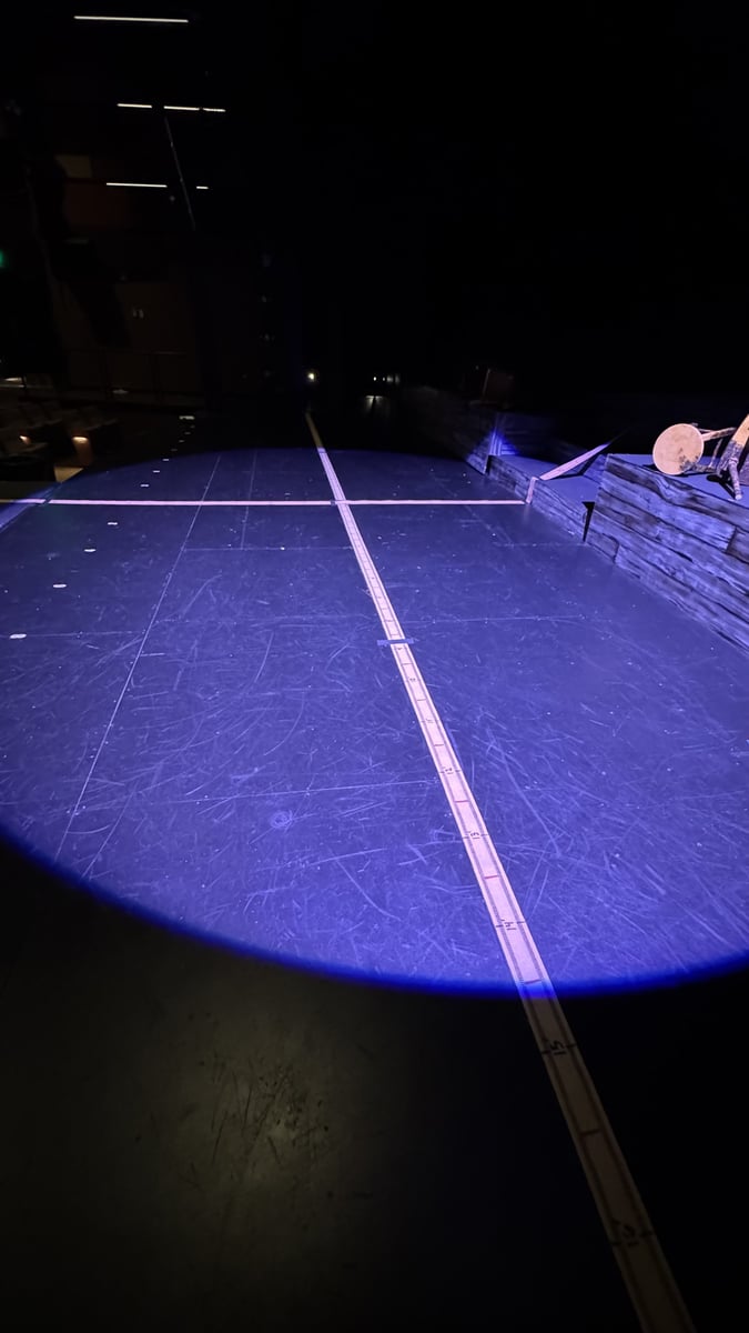 A low blue wash rakes across the bare stage during a focus session.