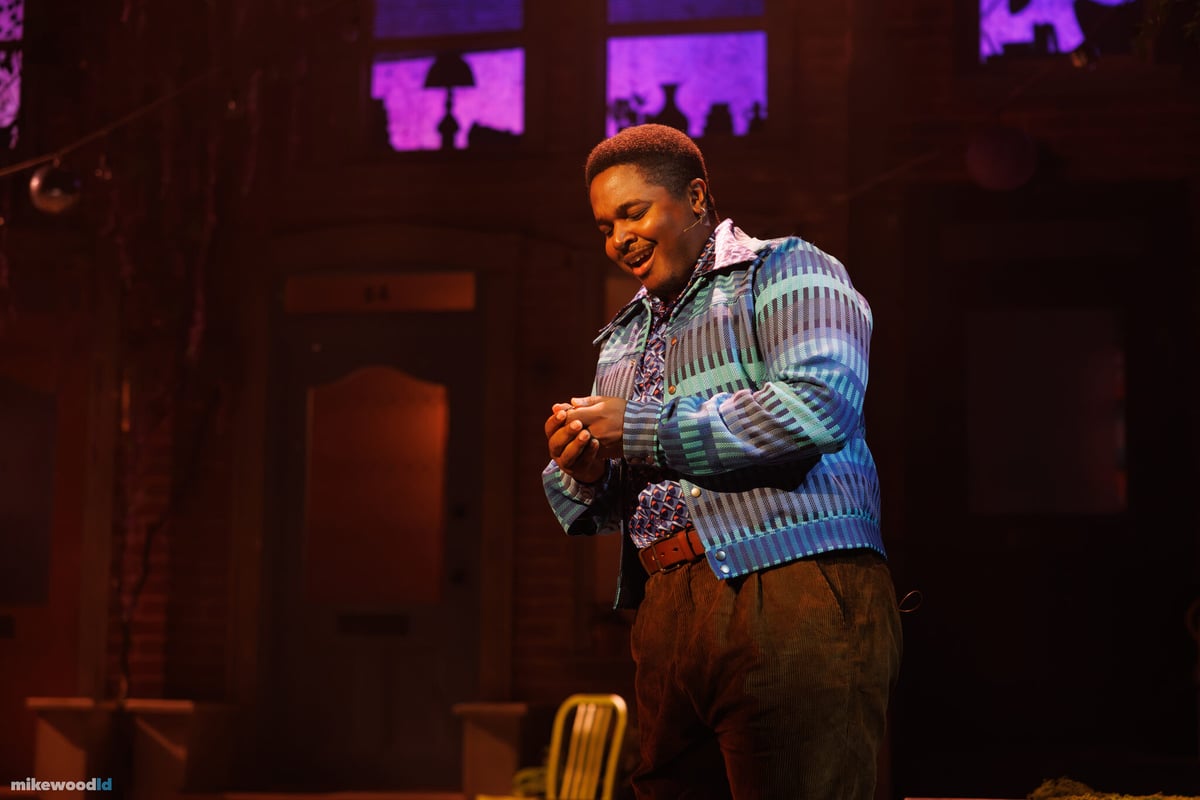 A performer smiles in a warm moment on the block-party street set in Dancin' In The Street.