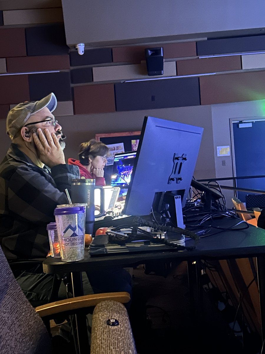 Mike Wood and Mack Scales work from the tech tables at the back of the house, console monitors and a Mountain Theatre Co. tumbler in front of them.