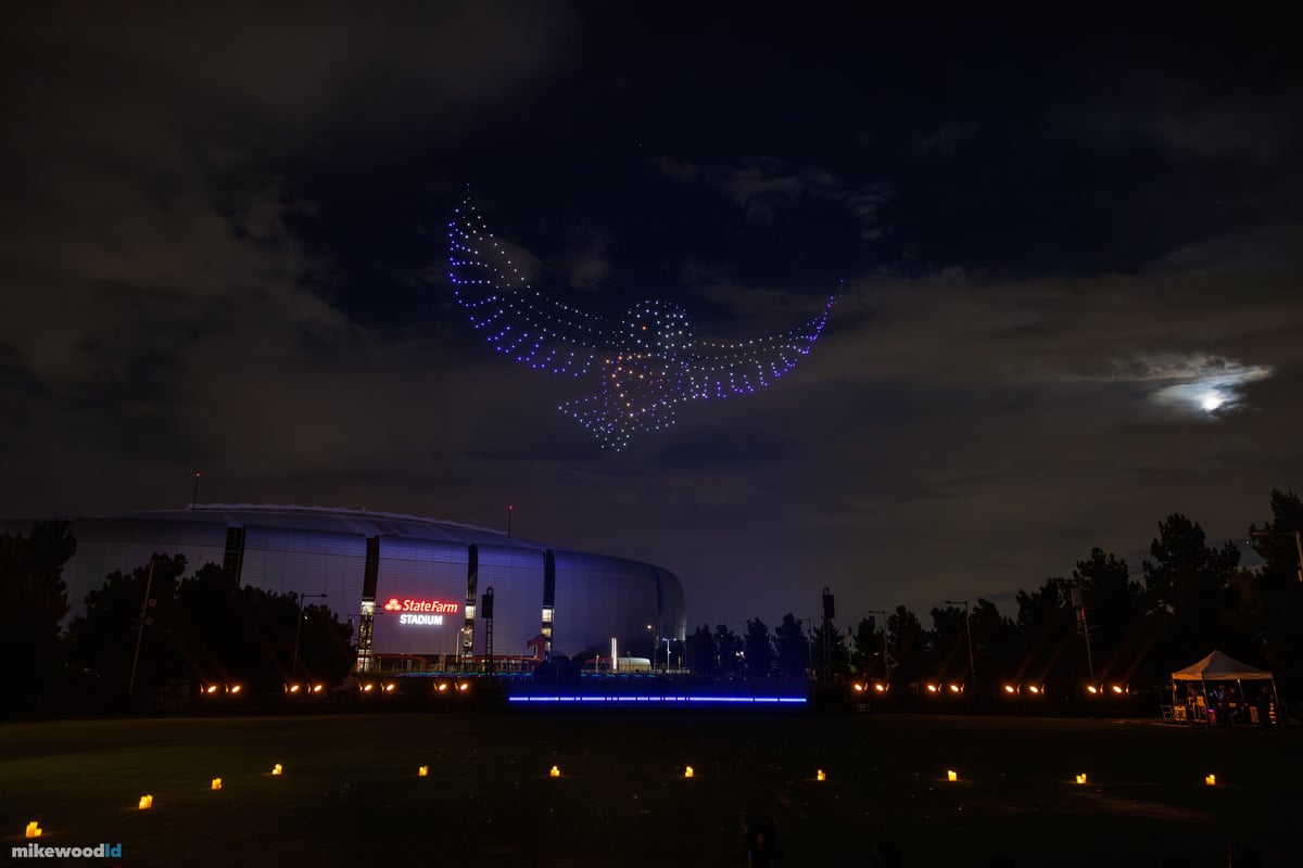Glowing green Golden Snitch drone formation hovering above the stadium with green stage wash and beams.