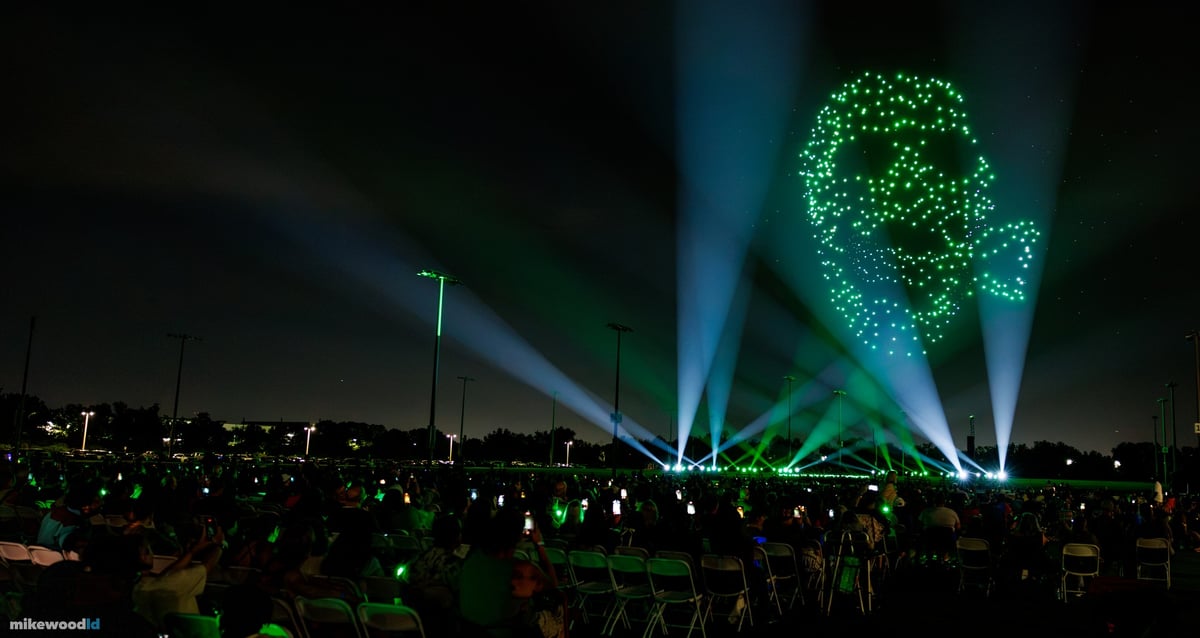 A green skull and serpent formation above the field, blue-white and green beams fanning up from the perimeter.
