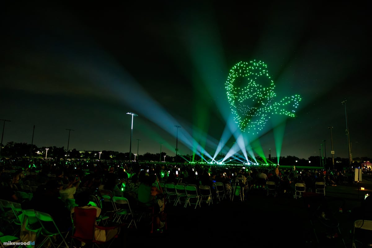 The green skull and serpent looming over the audience, teal and green beams converging beneath it.