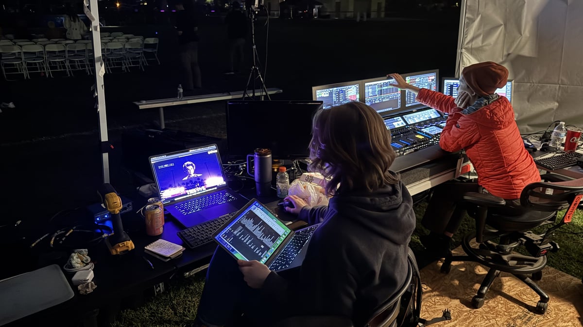 The team running the drone show from the tent at the field's edge at night.