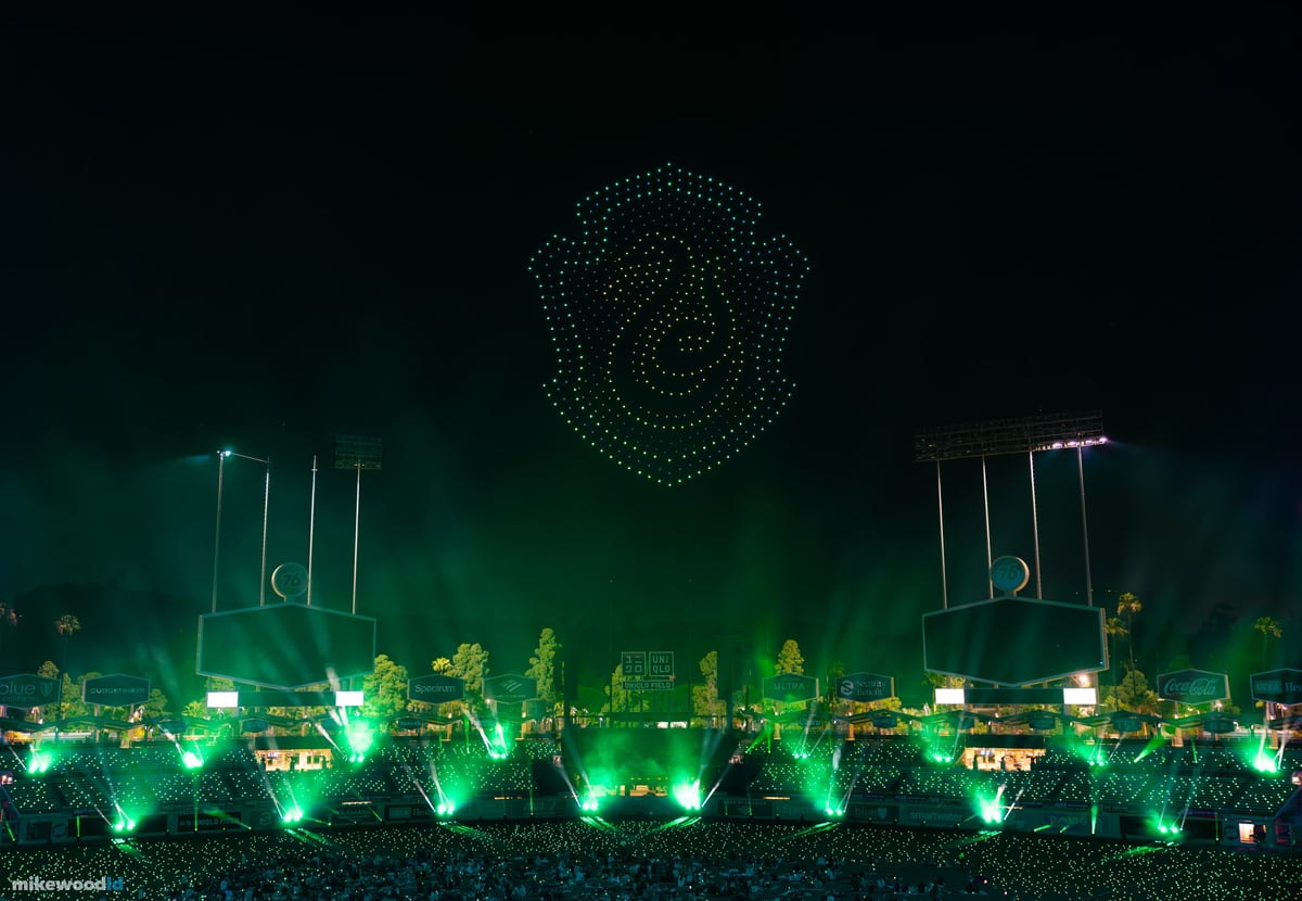 A coiled-serpent house crest in green drones above the field, the stadium and ground beams washed in matching green.