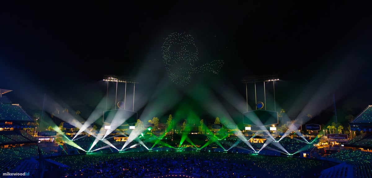 A green skull formation in drones above the field as beams crisscross from the stage in a symmetrical lattice across the bowl.