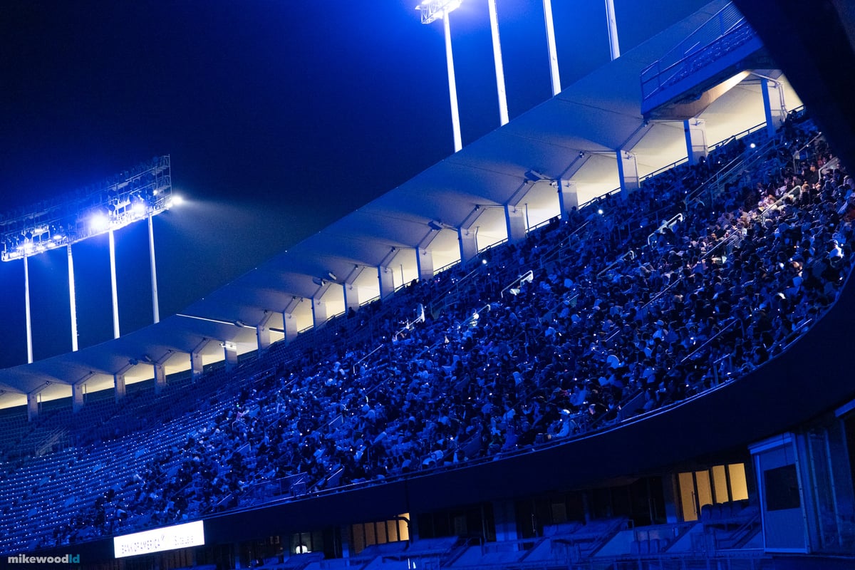 The packed stands of Dodger Stadium washed in blue light during the show, spectators filling every level beneath the stadium towers.