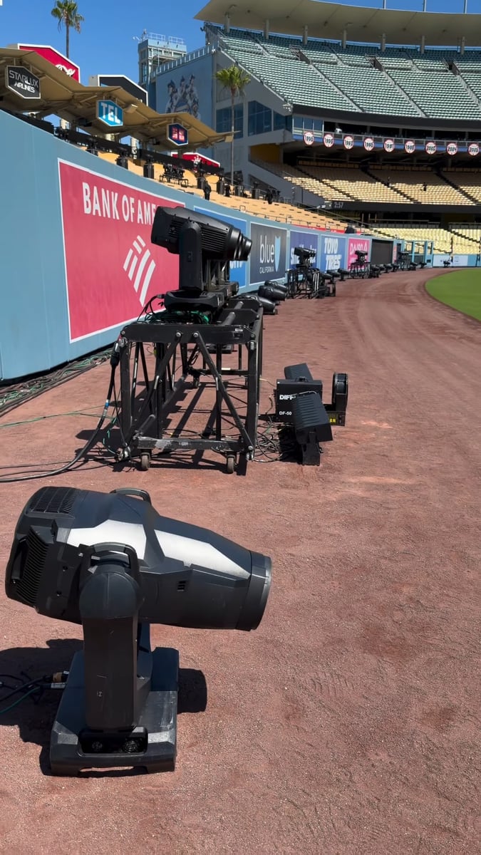 Moving lights staged along the Dodger Stadium warning track in daylight during load-in
