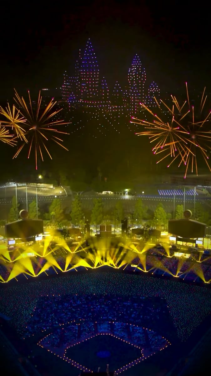 The drone castle glowing over Dodger Stadium with fireworks and yellow beams fanned across the field