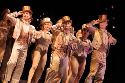 The company of A Chorus Line in gold finale costumes and top hats performing One at City Springs Theatre